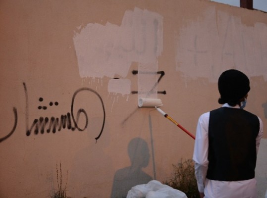 طلاب جامعة الباحة و”عاون” يزيلون الكتابات المشوهة للجدران