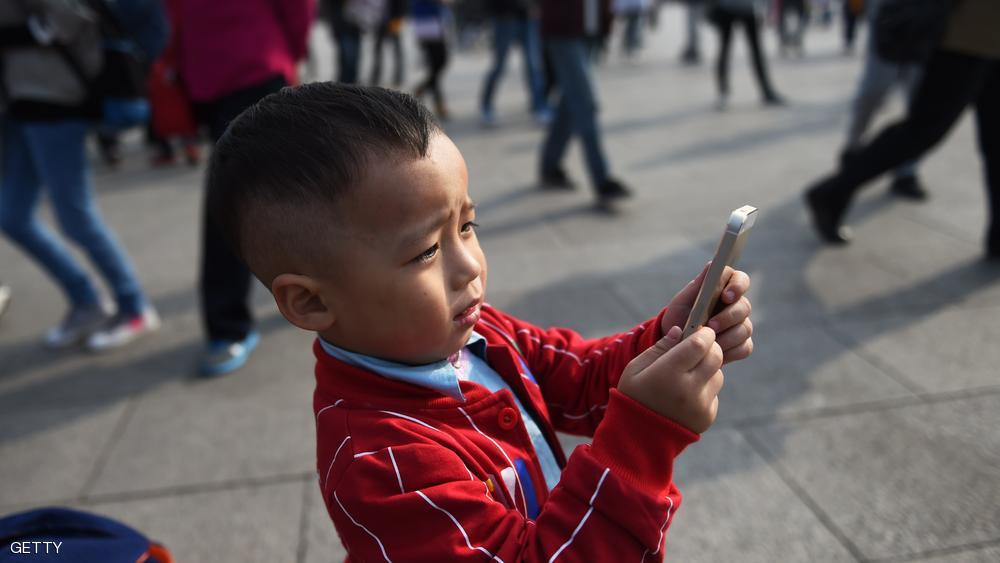 A young boy uses an iPhone to take photos in Tiananmen Square in Beijing on September 30, 2014. Apple said on September 30 it will begin selling its latest iPhones in China from October 17 after the Chinese regulator pressed the US giant to improve personal data security to gain approval. AFP PHOTO/Greg BAKER        (Photo credit should read GREG BAKER/AFP/Getty Images)