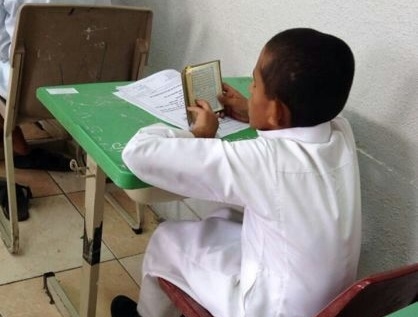 بالصورة.. طفل ينهي اختباره ويفتح مصحفه في قاعة الامتحان