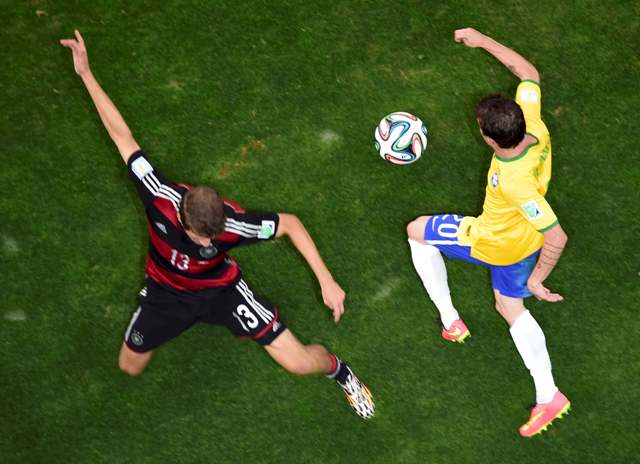Germany's Thomas Mueller (L) fights for the ball against Brazil's Bernard during their 2014 World Cup semi-finals at the Mineirao stadium in Belo Horizonte July 8, 2014. REUTERS/Francois Xavier Marit/Pool (BRAZIL - Tags: SOCCER SPORT WORLD CUP)