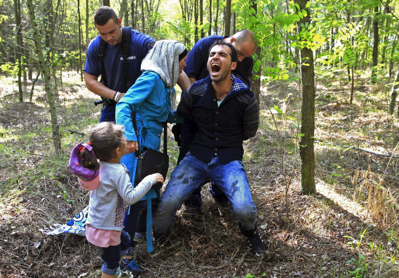 Hungarian policemen detain a Syrian migrant family after they entered Hungary at the border with Serbia, near Roszke, August 28, 2015. REUTERS/Bernadett Szabo          SEARCH "YEAREND 2015: MIGRANT CRISIS" FOR ALL 55 PICTURES