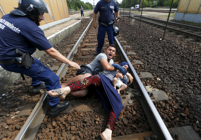 Hungarian policemen stand by the family of migrants as they wanted to run away at the railway station in the town of Bicske, Hungary, September 3, 2015. REUTERS/Laszlo Balogh     SEARCH "YEAREND 2015: MIGRANT CRISIS" FOR ALL 55 PICTURES