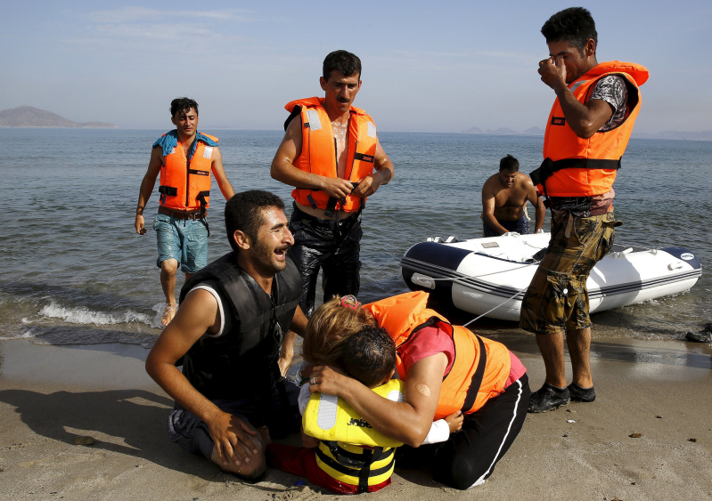 An Iranian migrant cries next to his son and wife moments after a small group of exhausted migrants from Iran arrive by paddling an engineless dinghy from the Turkish coast (seen in the background) at a beach on the Greek island of Kos August 15, 2015.  REUTERS/Yannis Behrakis     SEARCH "YEAREND 2015: MIGRANT CRISIS" FOR ALL 55 PICTURES