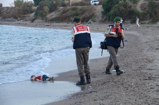 ATTENTION EDITORS - VISUAL COVERAGE OF SCENES OF DEATH OR INJURY A Turkish gendarmerie stands next to a young migrant, who drowned in a failed attempt to sail to the Greek island of Kos, as he lies on the shore in the coastal town of Bodrum, Turkey, September 2, 2015. At least 11 migrants believed to be Syrians drowned as two boats sank after leaving southwest Turkey for the Greek island of Kos, Turkey's Dogan news agency reported on Wednesday. It said a boat carrying 16 Syrian migrants had sunk after leaving the Akyarlar area of the Bodrum peninsula, and seven people had died. Four people were rescued and the coastguard was continuing its search for five people still missing. Separately, a boat carrying six Syrians sank after leaving Akyarlar on the same route. Three children and one woman drowned and two people survived after reaching the shore in life jackets.  REUTERS/Nilufer Demir/DHA  ATTENTION EDITORS - NO SALES. NO ARCHIVES. FOR EDITORIAL USE ONLY. NOT FOR SALE FOR MARKETING OR ADVERTISING CAMPAIGNS. TEMPLATE OUT. THIS IMAGE HAS BEEN SUPPLIED BY A THIRD PARTY. IT IS DISTRIBUTED, EXACTLY AS RECEIVED BY REUTERS, AS A SERVICE TO CLIENTS. TURKEY OUT. NO COMMERCIAL OR EDITORIAL SALES IN TURKEY.