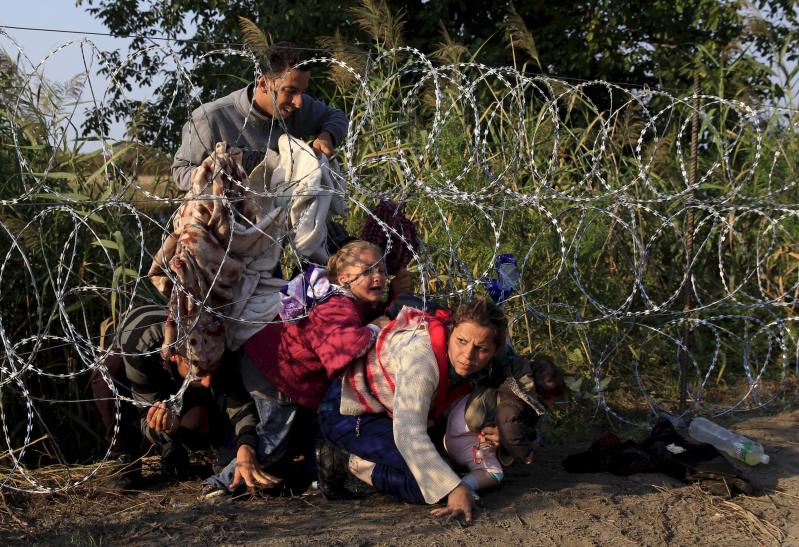 Syrian migrants cross under a fence as they enter Hungary at the border with Serbia, near Roszke, August 27, 2015.   REUTERS/Bernadett Szabo      SEARCH "YEAREND 2015: MIGRANT CRISIS" FOR ALL 55 PICTURES