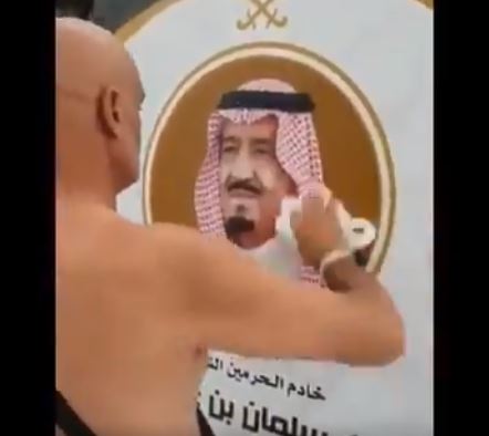 فيديو معبر .. حاج يزيل آثار المطر عن صورة الملك سلمان