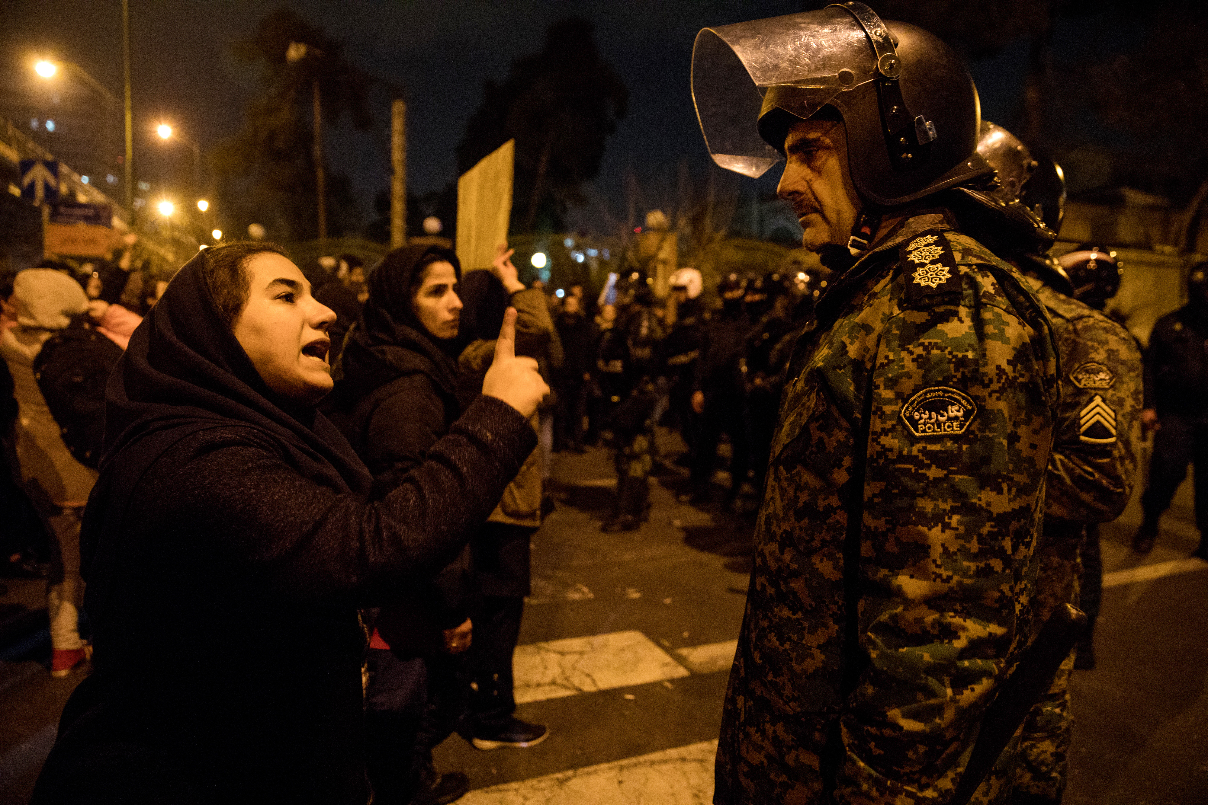 A woman attending a candlelight vigil, in memory of the victims of Ukraine International Airlines Boeing 737, talks to a policeman following the gathering in front of the Amirkabir University in the Iranian capital Tehran on January 11, 2020. (Photo by Mona HOOBEHFEKR / ISNA / AFP)
