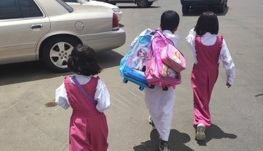 صورة عفوية.. طفل يحمل حقيبتي أختيه