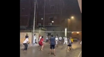 شباب يمارسون لعبة الكرة الطائرة تحت زخات المطر