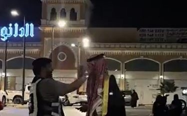 رجل مرور يعدّل شماغ رجل أثناء الاحتفال باليوم الوطني