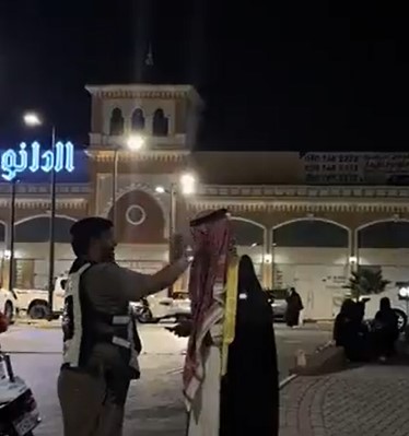 رجل مرور يعدّل شماغ رجل أثناء الاحتفال باليوم الوطني