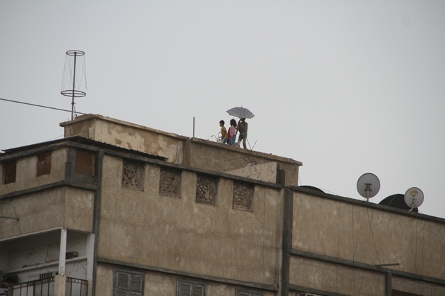 خطورة.. أطفال يراقبون الأمطار من حافة سور السطح