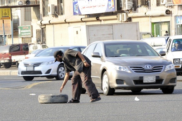 بالصور.. مقيم يغامر بحياته ليزيل إطاراً في تقاطع بـ”جدة”