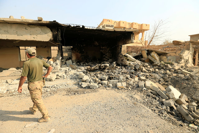 A member of Iraqi security forces walks past a destroyed building by clashes in Hammam al-Ali, south of Mosul, Iraq November 7, 2016. REUTERS/Thaier Al-Sudani