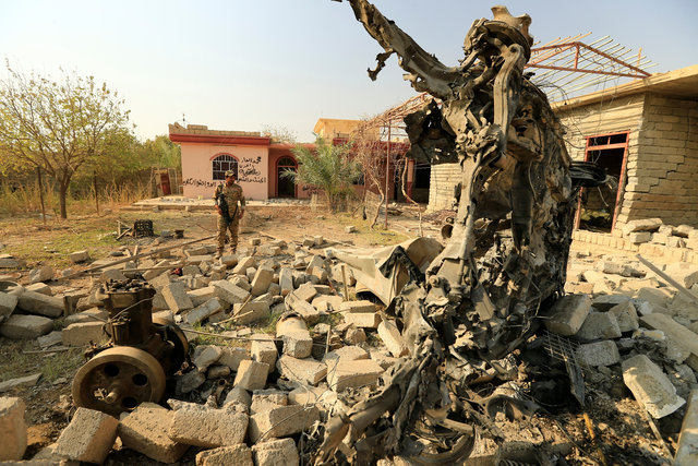 A member of Iraqi security forces inspects a wreckage of a vehicle destroyed by clashes in Hammam al-Alil, south of Mosul, during an operation to attack Islamic State militants in Mosul, Iraq November 7, 2016. REUTERS/Thaier Al-Sudani