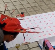 بالفيديو.. شاب يكتب اللغة الصينية برأسه على الطريق